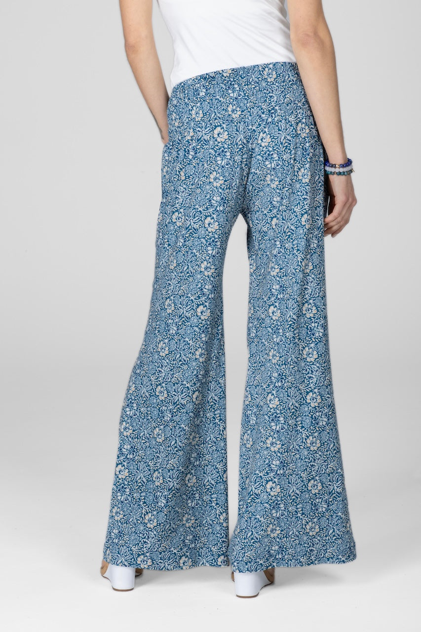 Back view of woman wearing blue batik printed portofino wide leg pant with high rise smocked waistband