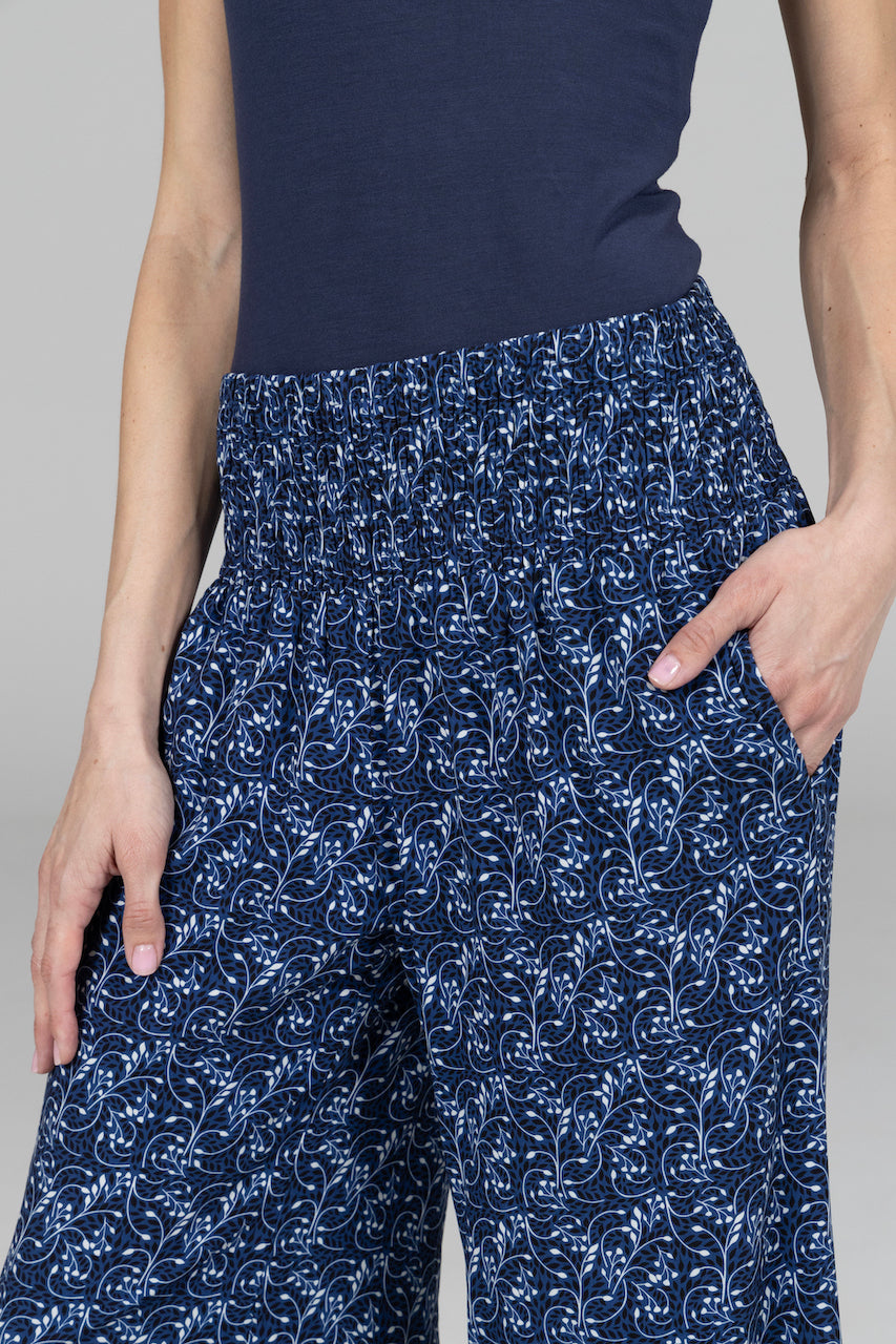 Close up of woman wearing blue vines pants with high rise smocked waistband

