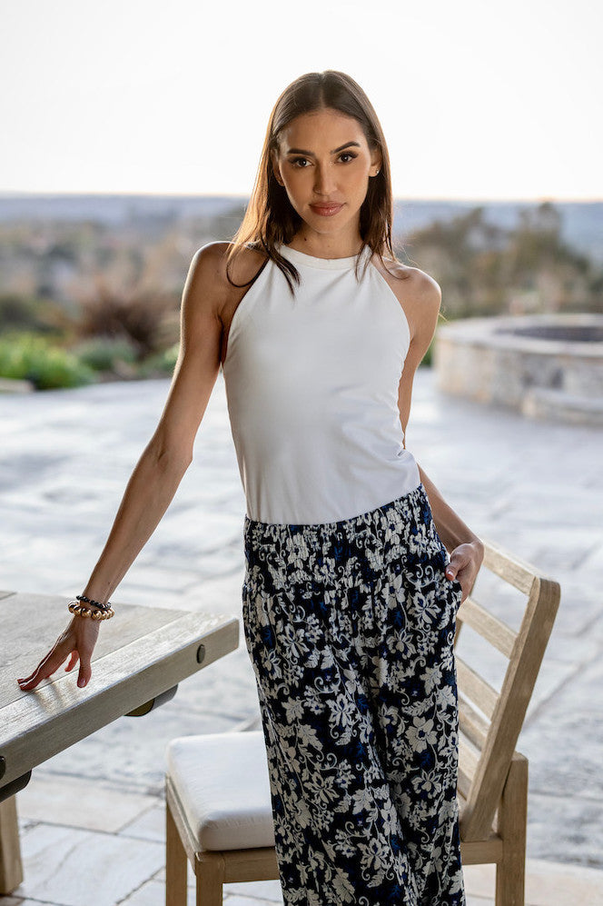 Model wearing the Grace Yoga Halter in white, paired with blue printed pants, showcasing a stylish and vibrant outfit perfect for yoga or casual outings