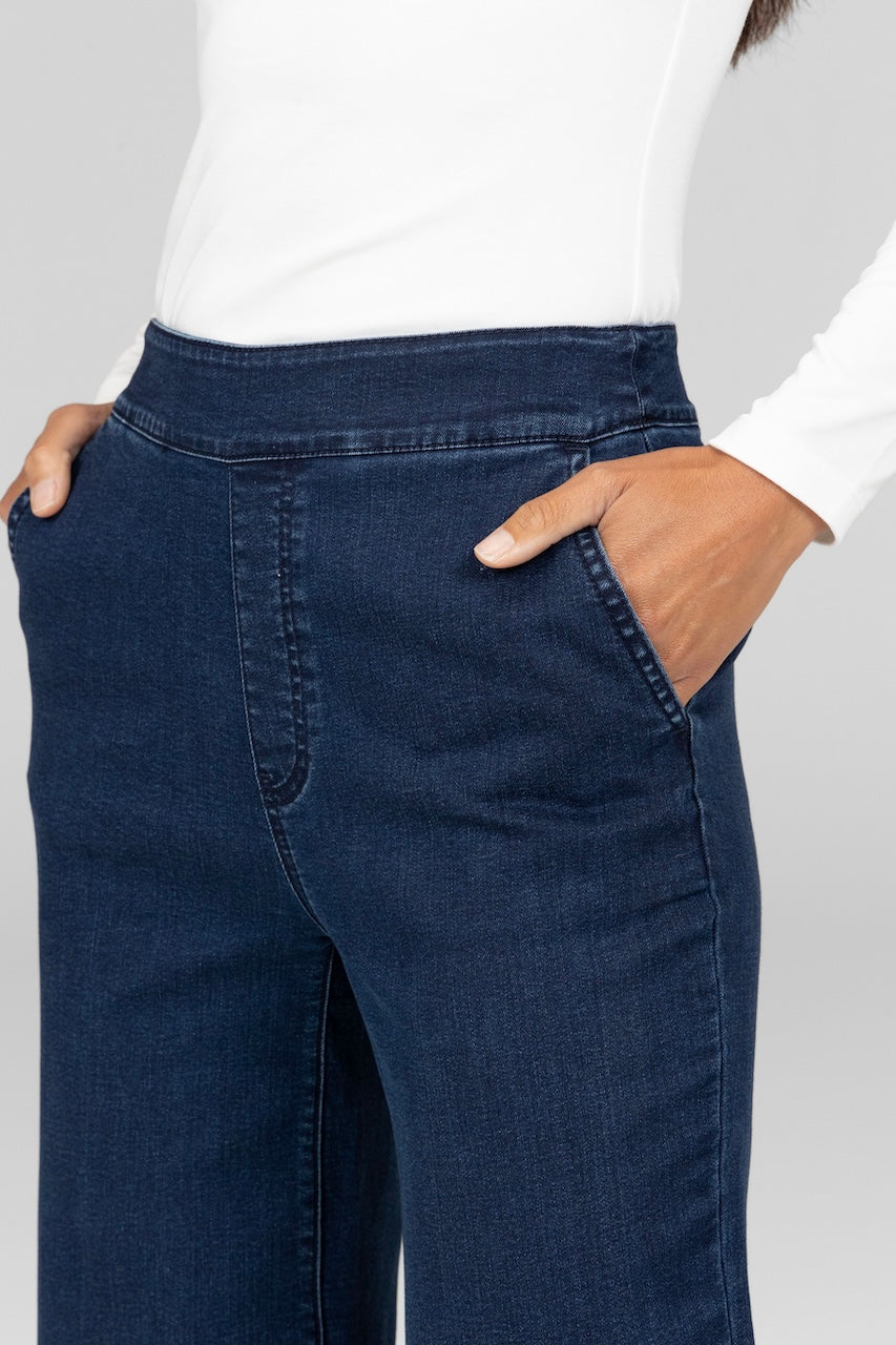 Close up image of woman wearing dark wash stretch denim trousers with pockets