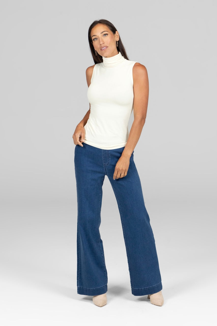Woman wearing ivory sleeveless turtleneck paired with light wash denim pants