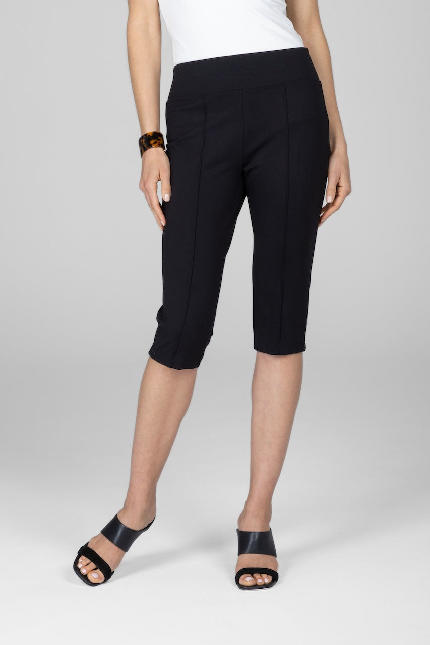 A pair of black knee-length pants with a high waistband and pintuck detailing, worn with a white top and black sandals.