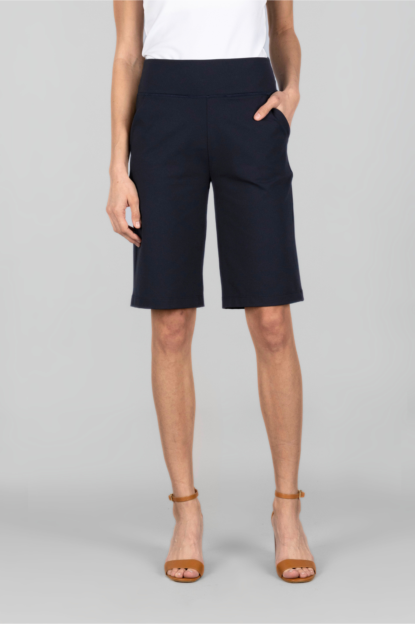 A model wearing black bermuda shorts with a white top, the shorts have a mid-thigh length and a straight fit.