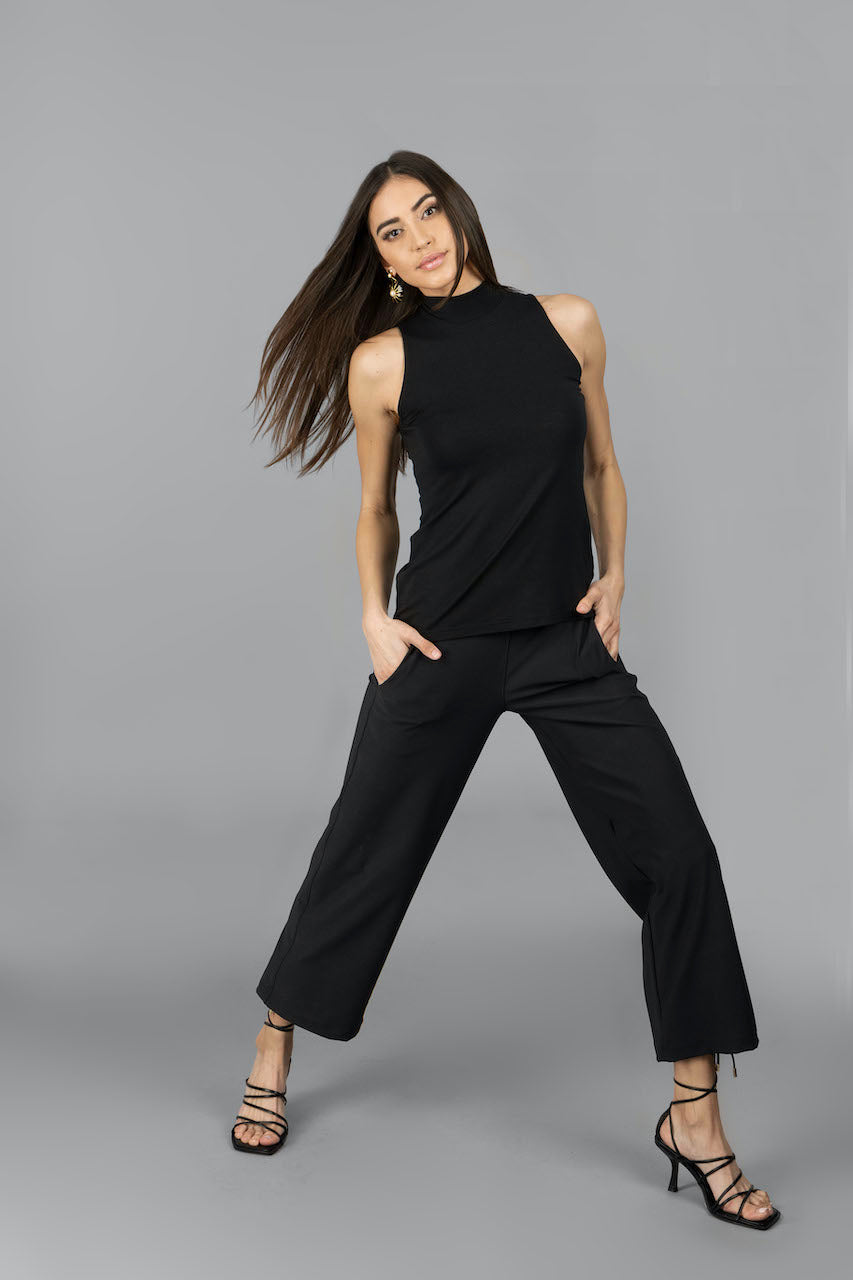 Woman wearing black sleeveless mockneck top with matchign black ankle pants