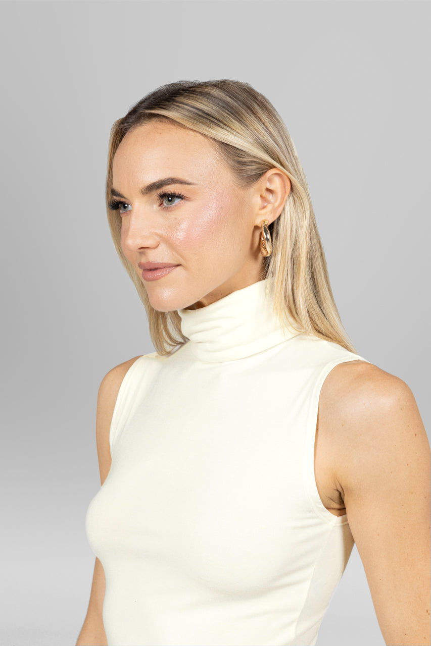 Close up view of woman wearing ivory sleeveless turtleneck