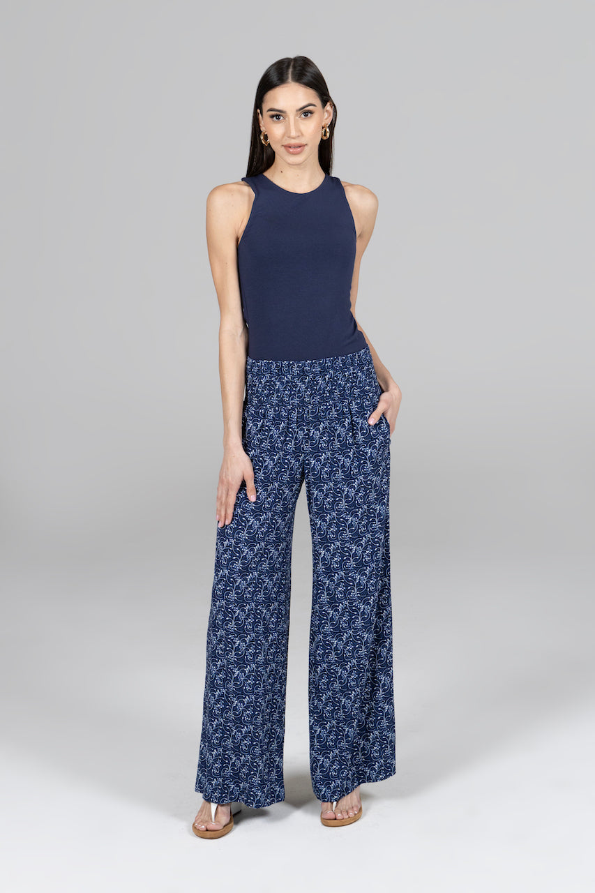 Woman wearing comfortable blue vines printed pants. High rise fit with smocked waistband and wide leg opening

