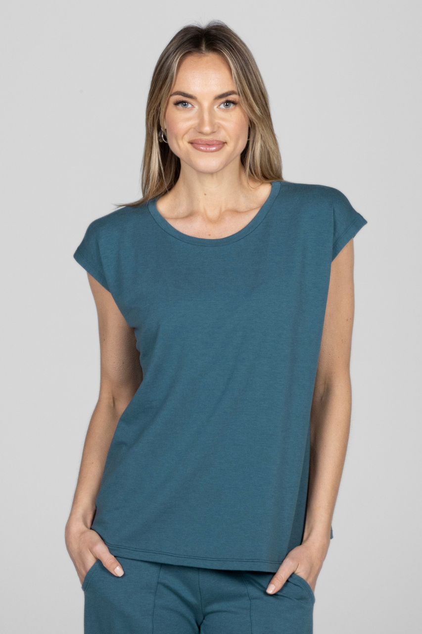 A woman wearing a teal short sleeve top with a boat neckline.