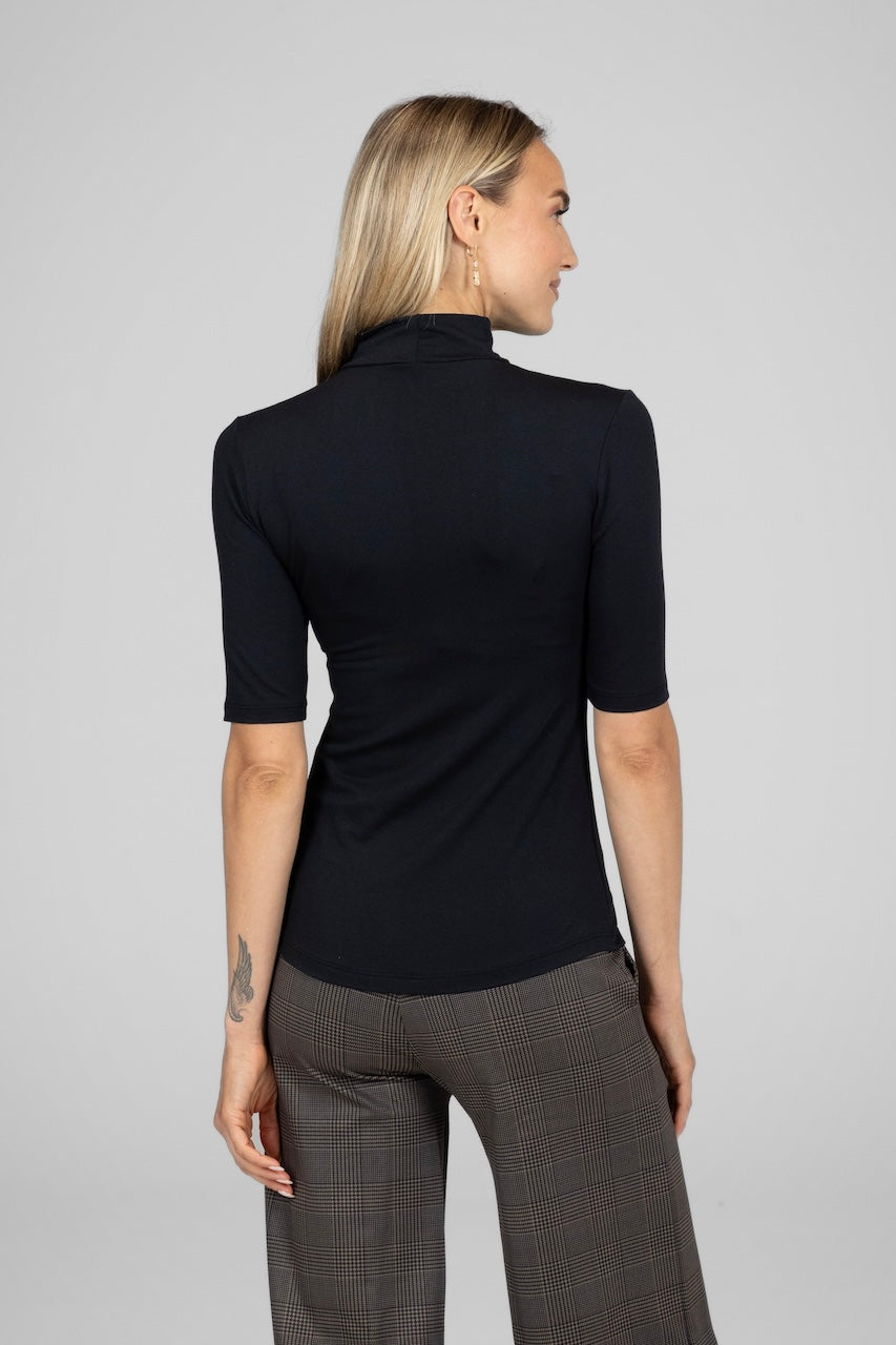 Woman wearing Black Grace mockneck tee with a fitted silhouette and brown plaid pants