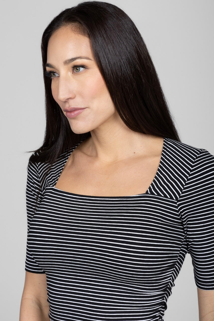 Close up view of woman wearing black and white striped top with square neck and short sleeve