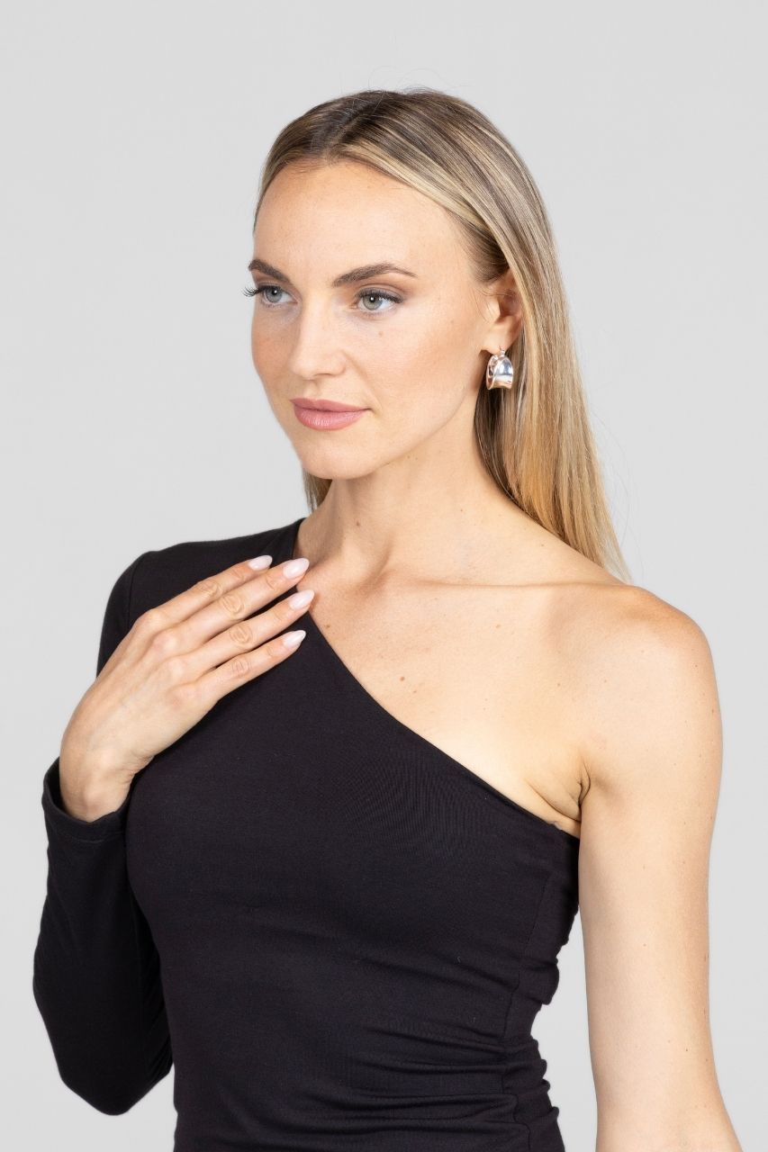 Woman wearing a black one-shoulder top against a plain background