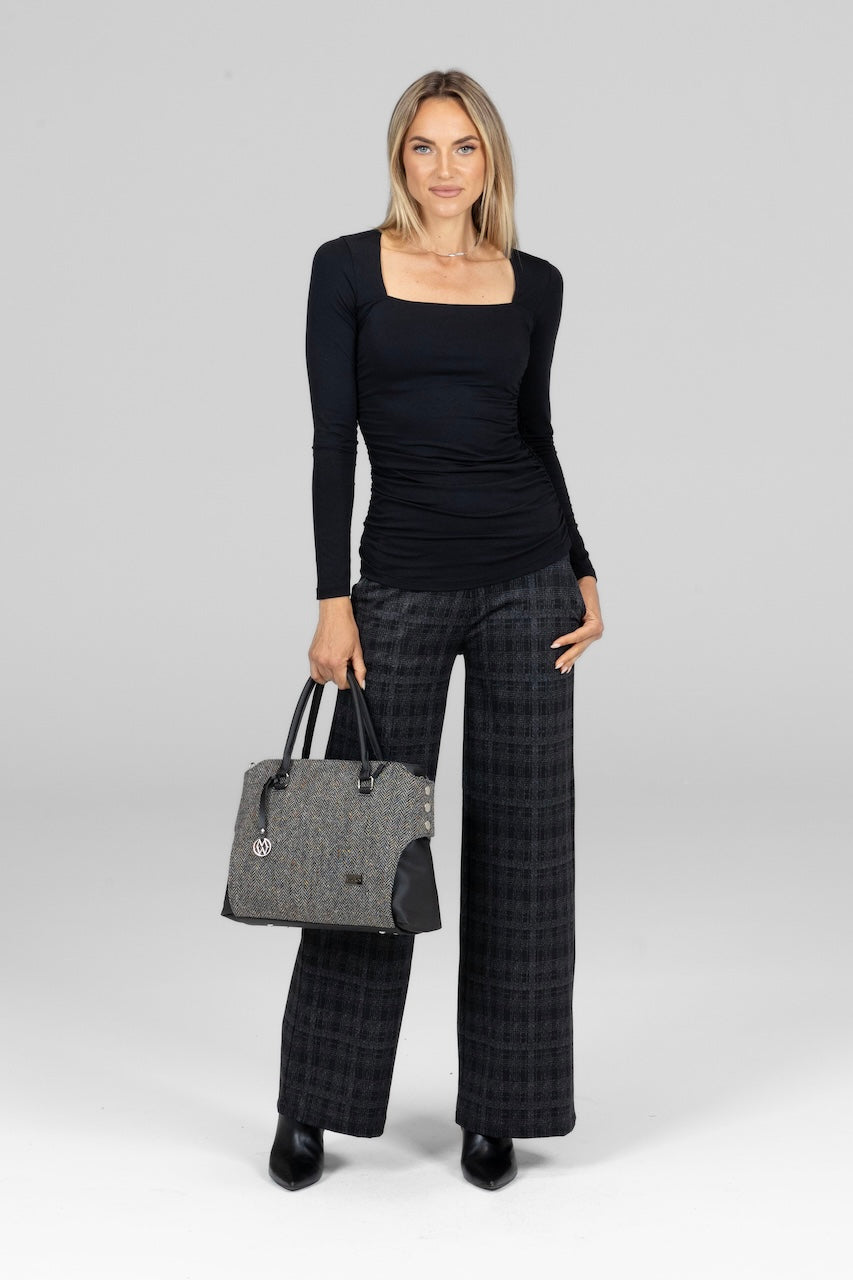 Woman wearing black square neck long sleeve top with high waist wide leg grey plaid pants