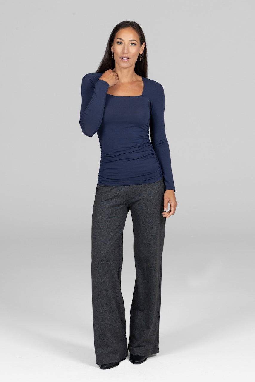Full length photo of woman wearing long sleeve navy blue top with charcoal grey high waist wide leg pants