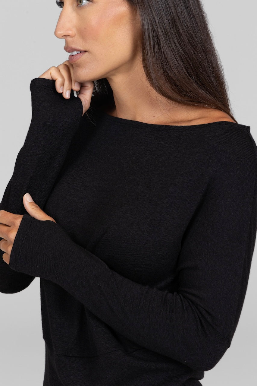 Close up view of woman wearing black boatneck long sleeve sweater
