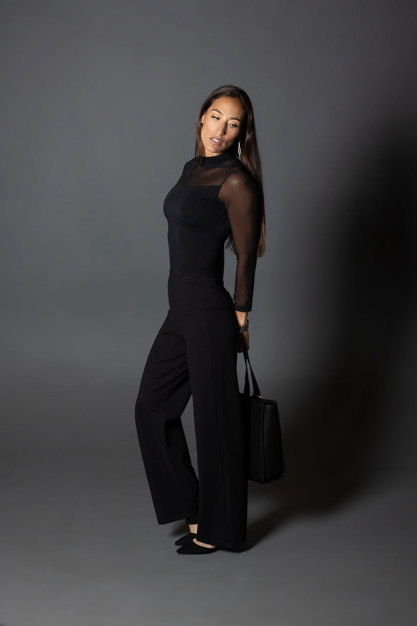 Woman posing wearing a long sleeve mesh top with black wide leg pants