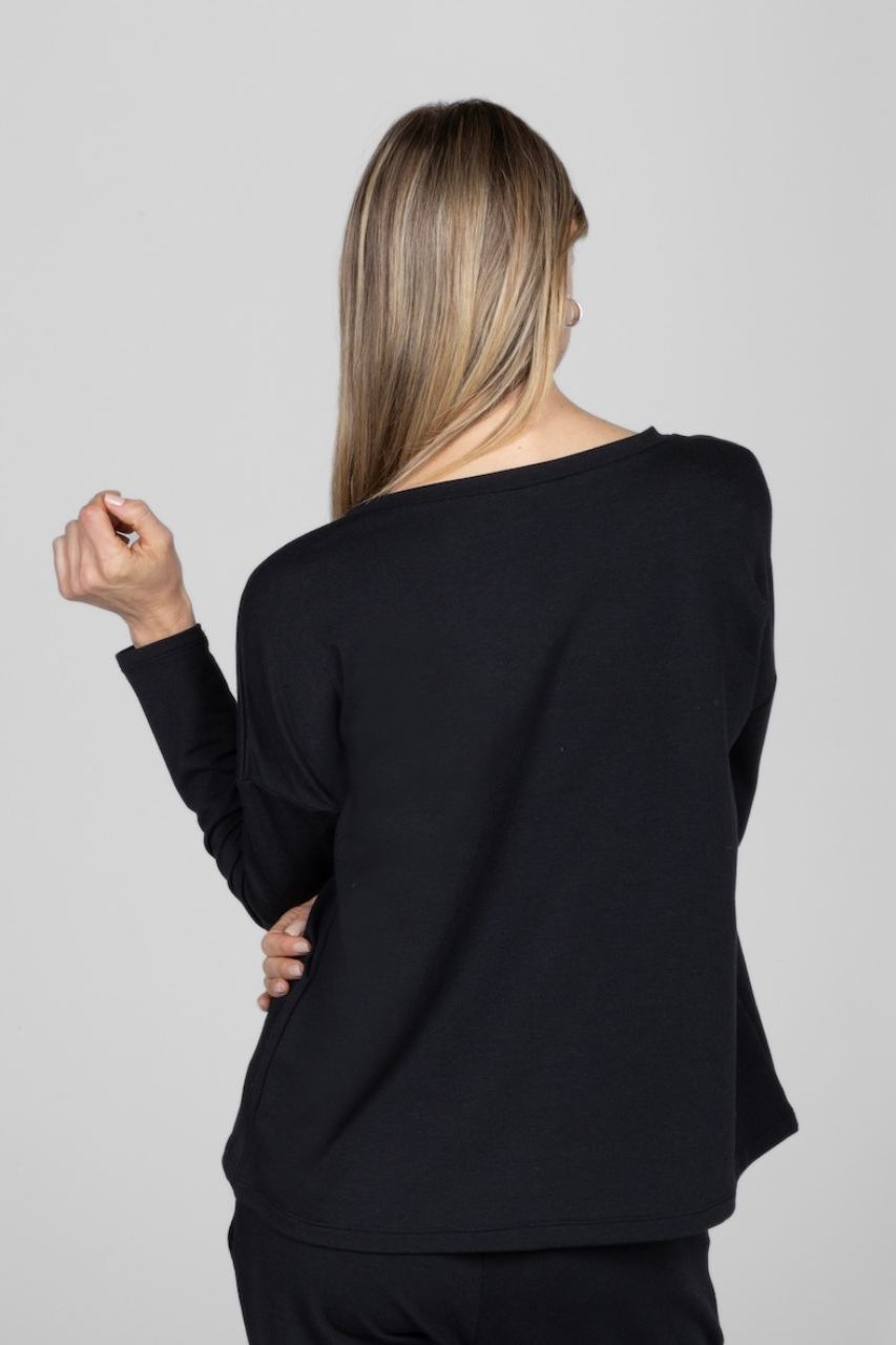 Back view of woman wearing black long sleeve with one arm up