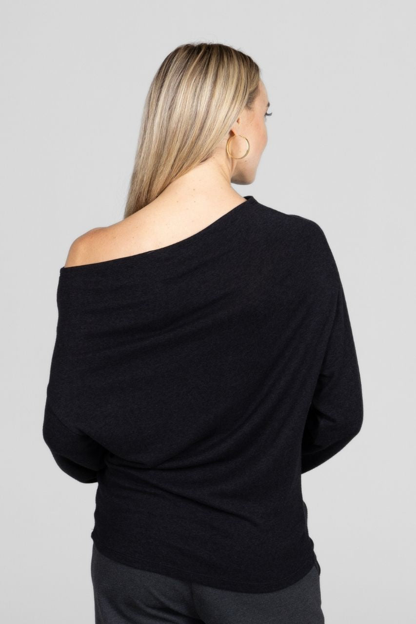 Back view of a woman wearing a black off-shoulder top against a gray background
