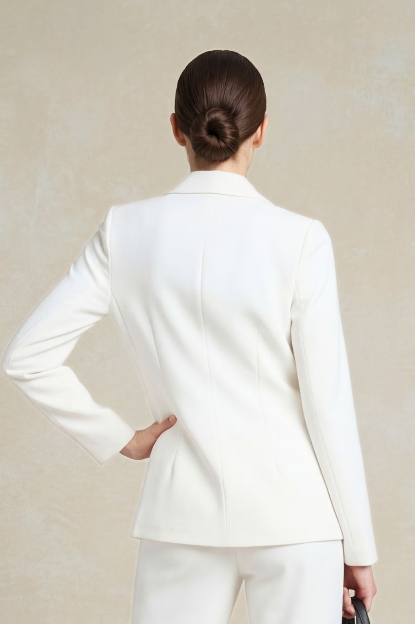 Person wearing a white suit against a beige background