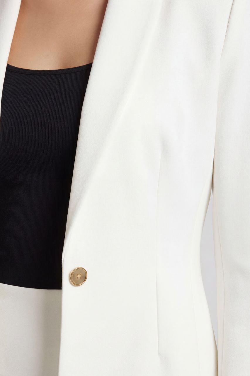 White blazer with a gold button on a white background