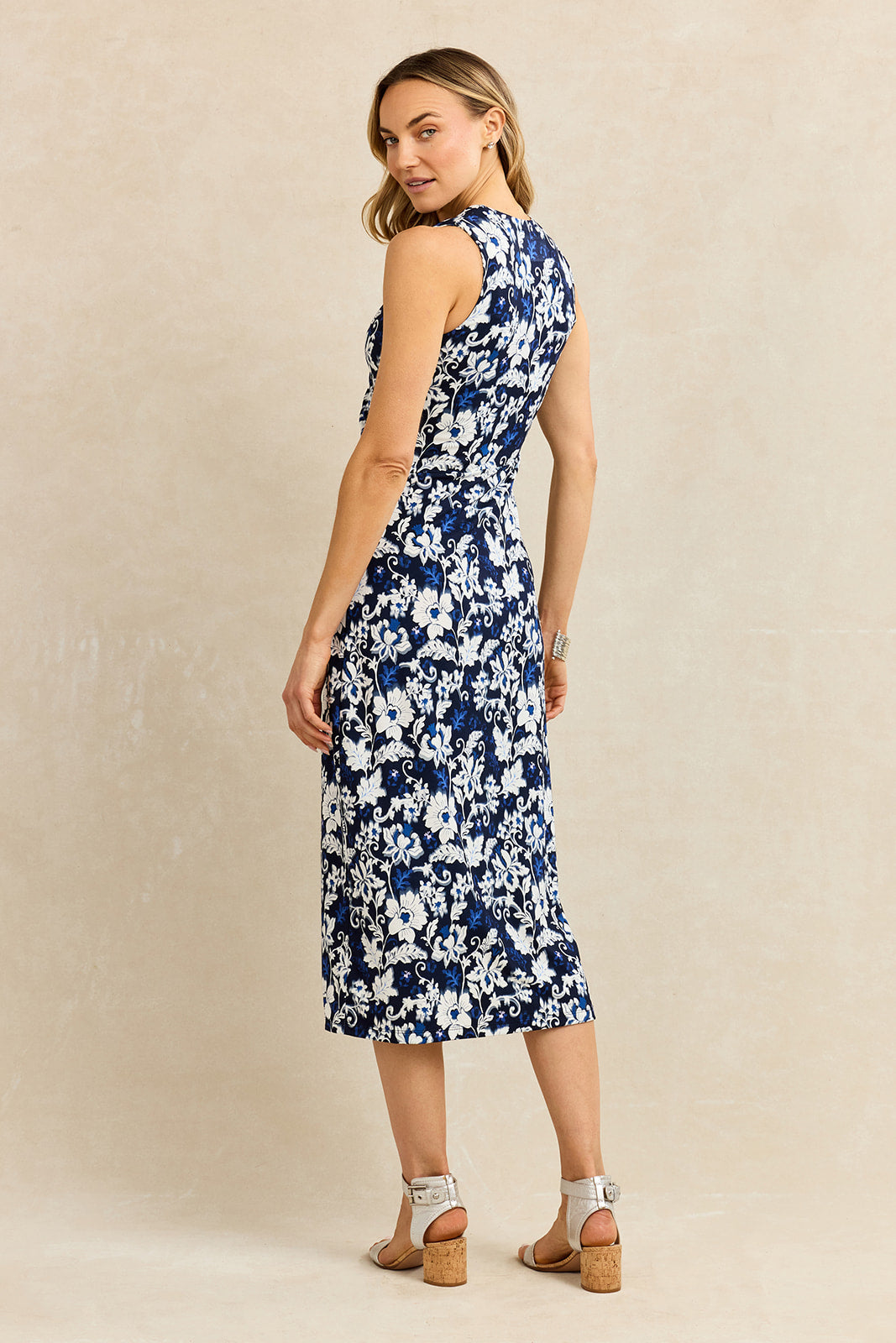 Back view of a woman wearing a navy floral dress against a beige background