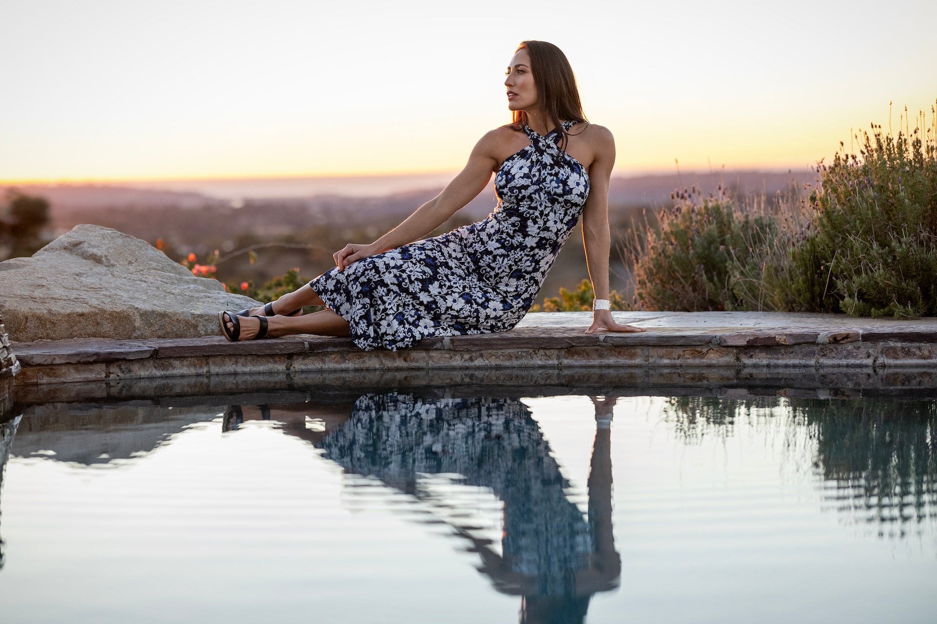 Model sitting in a side pose in LUXE HALTER MIDI DRESS: LILY IKAT