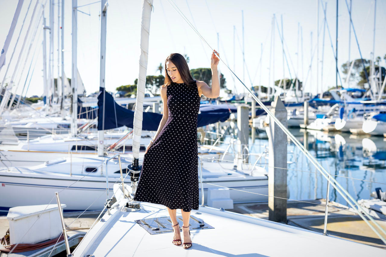 Model on a boat in BOATNECK MIDI DRESS: NAVY DOT