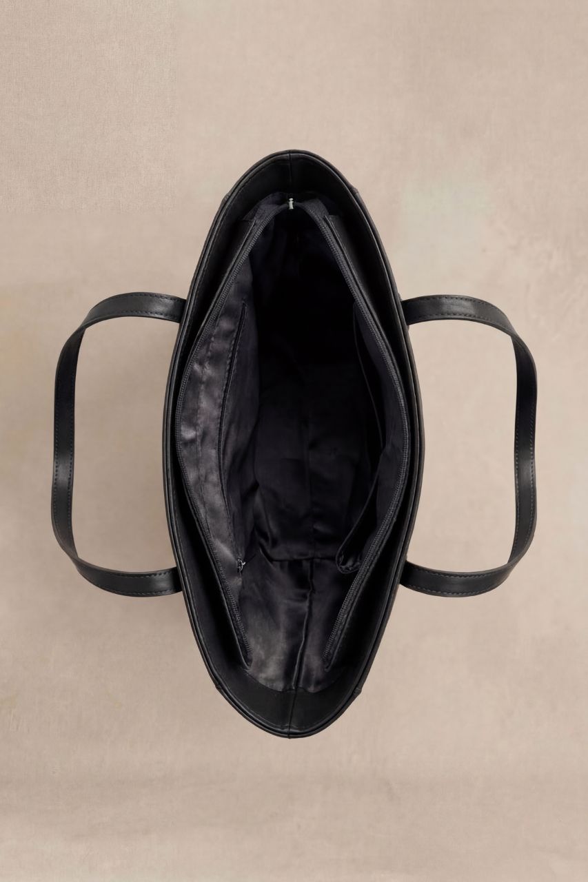 Inside view of a black PU leather handbag on a beige background