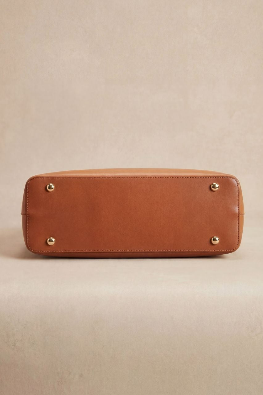 Bottom view of a brown PU leather handbag on a beige background