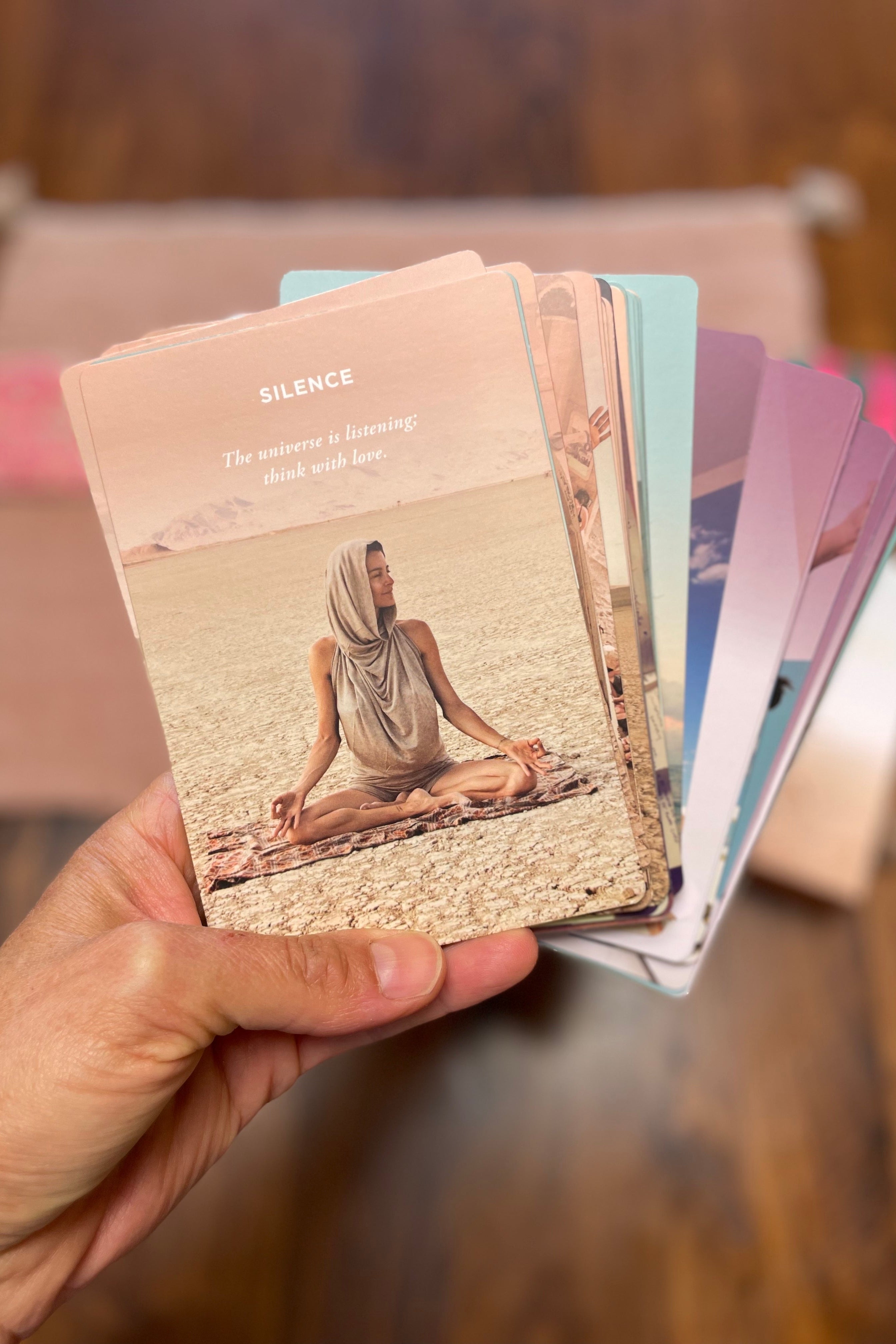 Hand holding a deck of yoga cards with a person in a meditative pose on one card.