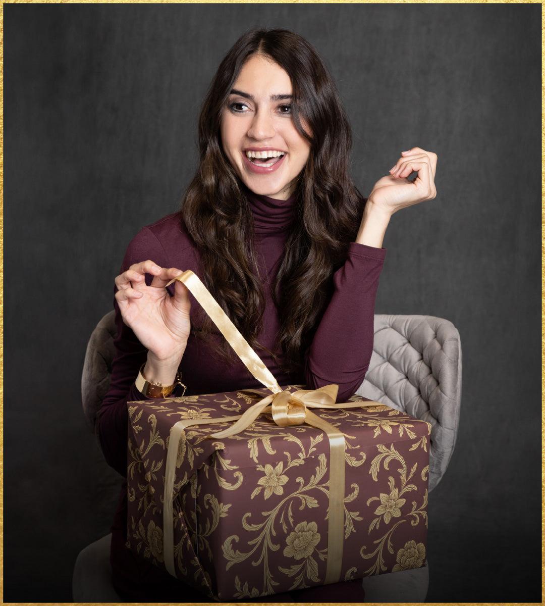 Woman opening a gift box with a gold ribbon against a dark background
