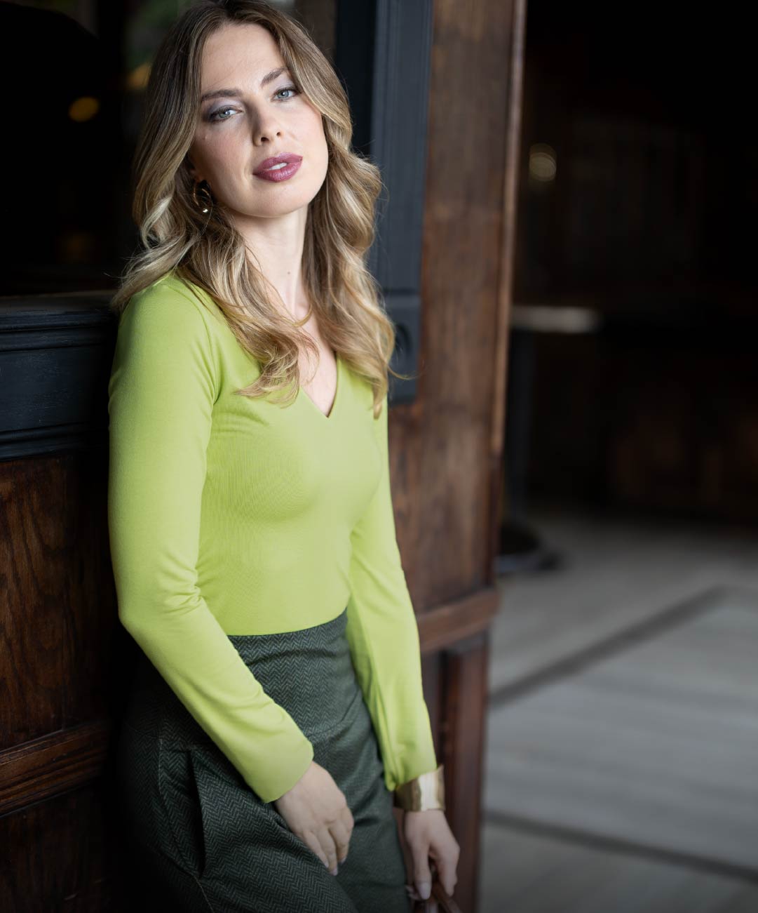 Woman wearing a bright green v-neck top in an indoor setting