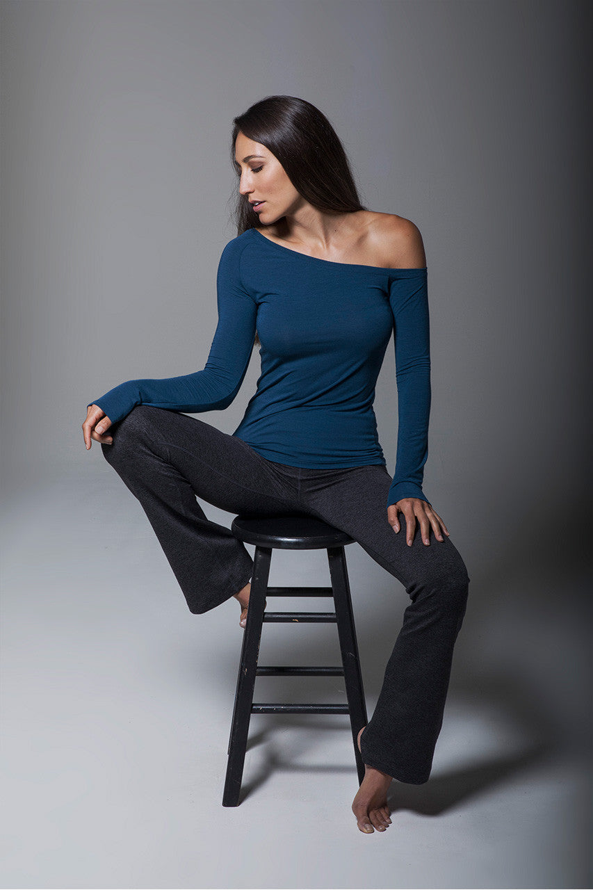 Woman sitting on a stool, wearing an off-the-shoulder top paired with the Ultra High Waist Goddess Bootcut in charcoal heather, highlighting the stylish combination and relaxed fit.