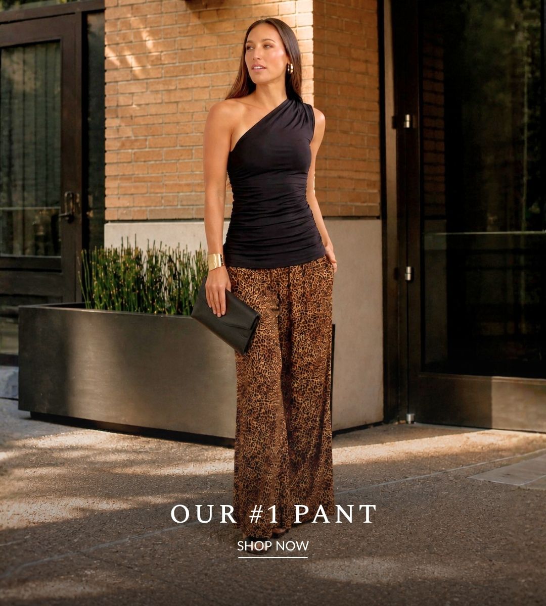 Woman wearing leopard pants and black one shoulder top on the sidewalk