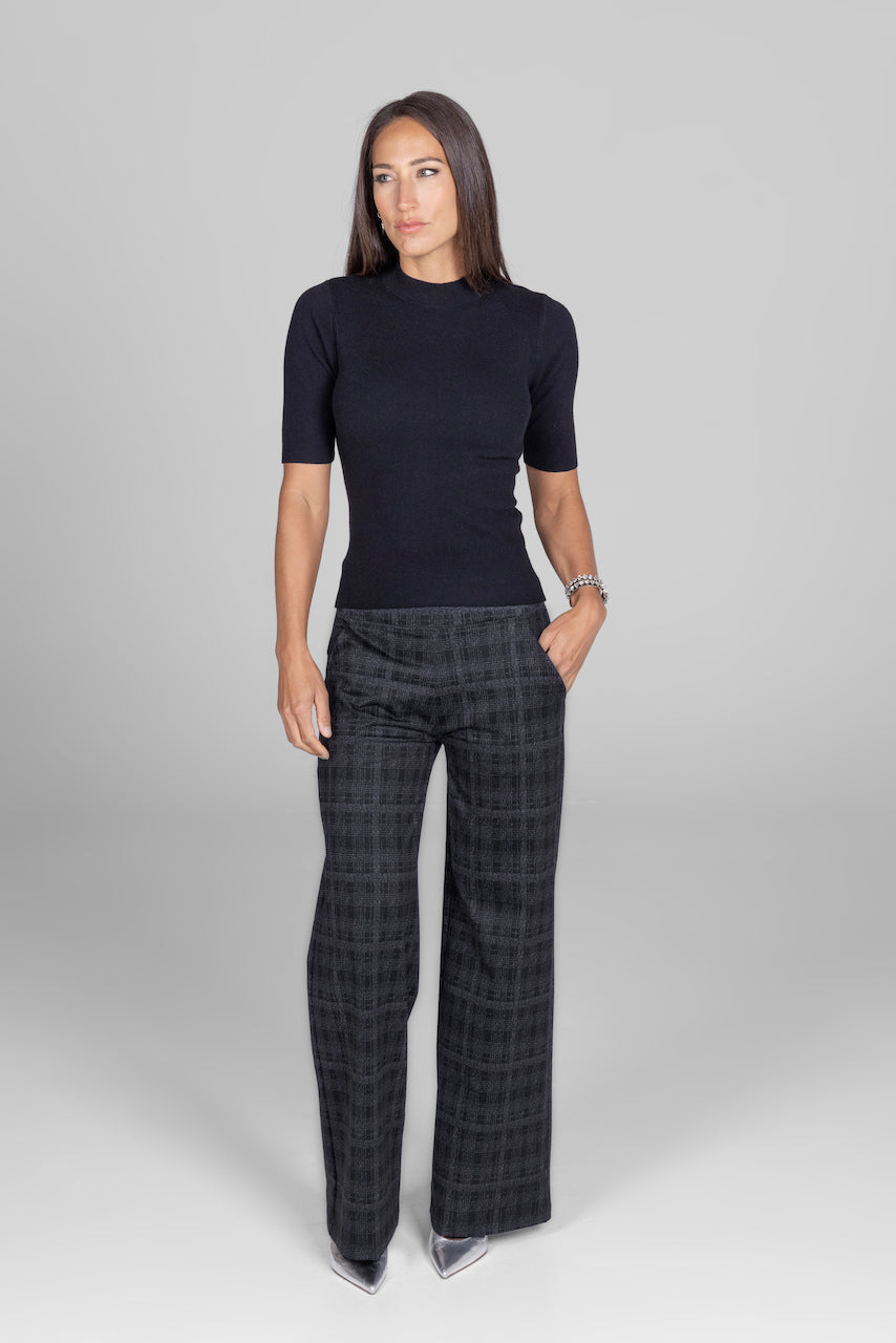 Woman wearing black short sleeve top with grey high waist wide leg plaid pants