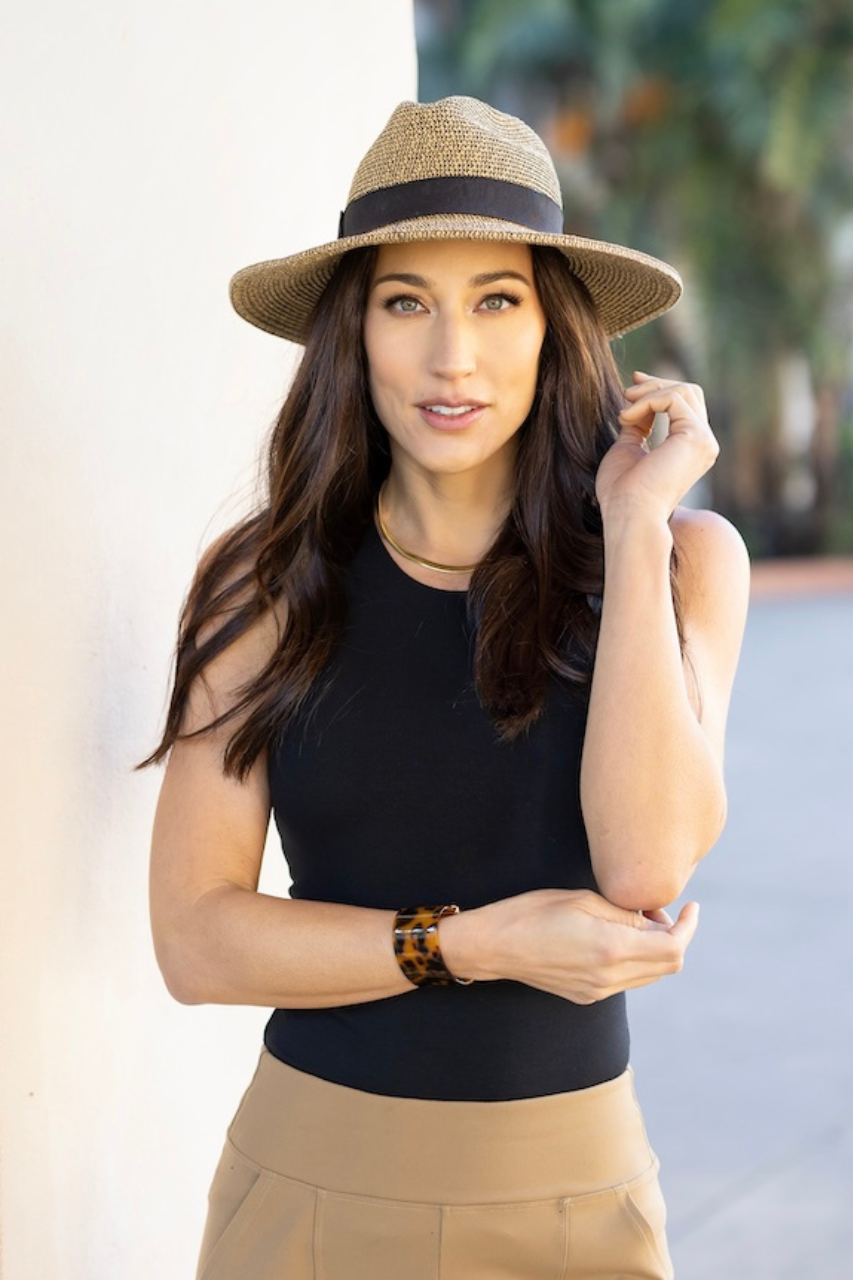 Woman wearing straw hat and black tank top with khaki trousers