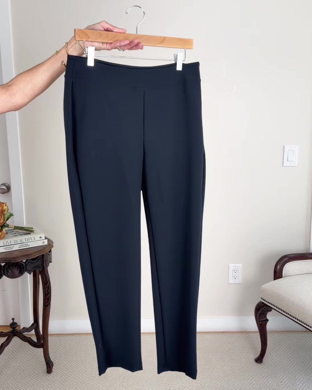 Model putting together outfits consisting of black ankle pants, white tops, a black blazer, flats, sunglasses, a black handbag and a gold clutch bag