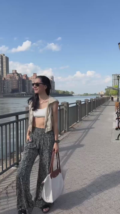 Woman wearing black paisley pants walking along a river