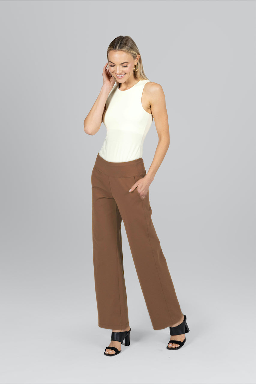Woman wearing white tank top with dark khaki traveler pants